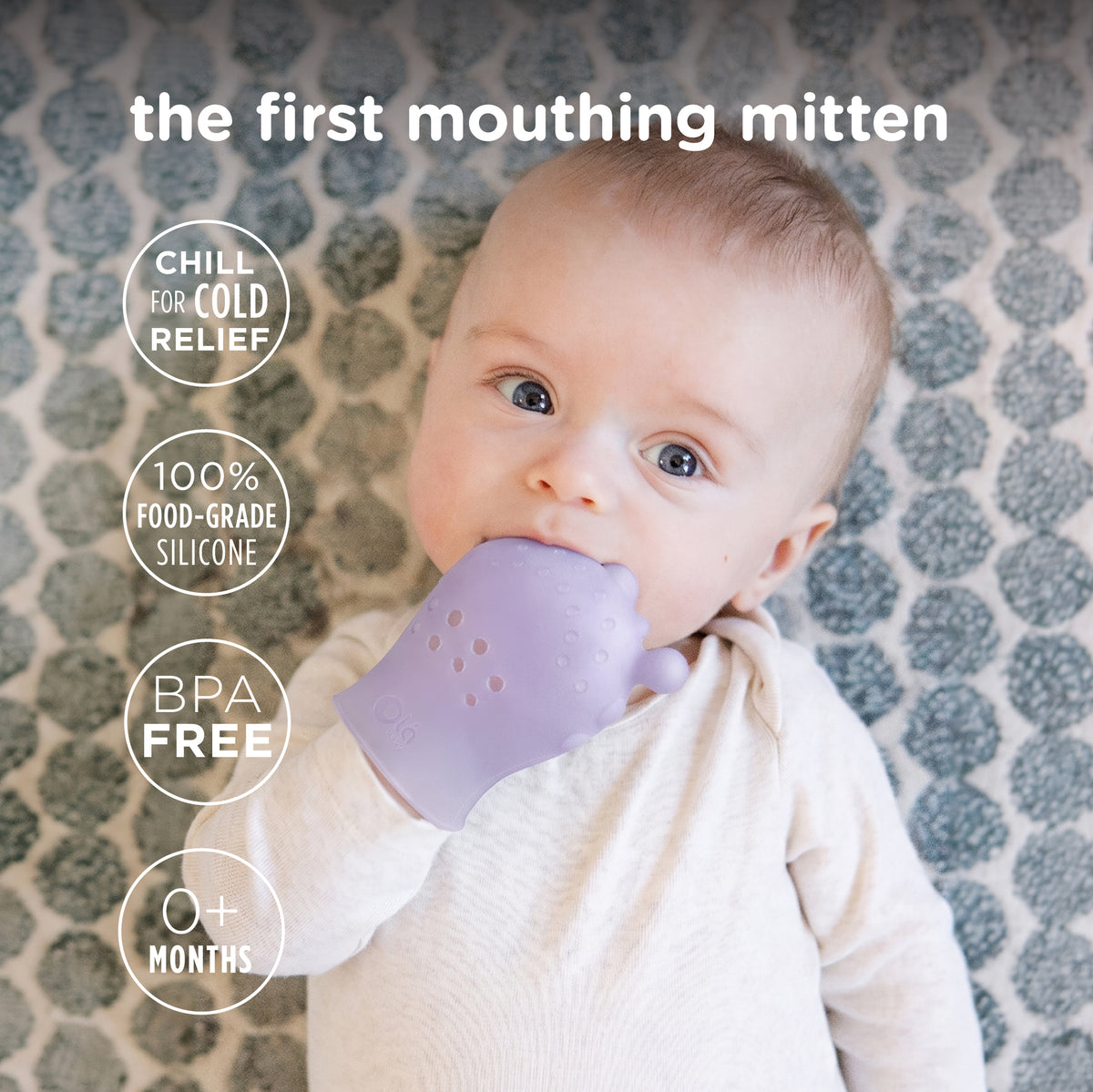A happy infant wearing and chewing on a lavender Olababy silicone mouthing mitten to soothe teething gums.