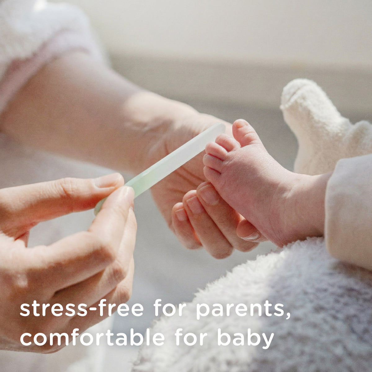 A parent easily and safely filing their baby's tiny toenails with a comfortable Olababy glass nail file.
